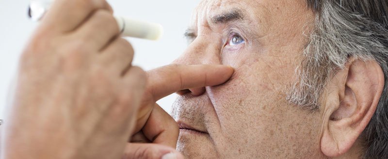 An ophthalmologist examining eye of an elderly man