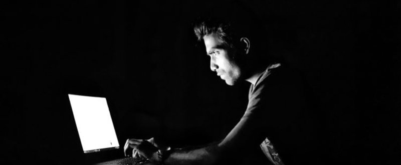 A man staring at a computer screen in the dark